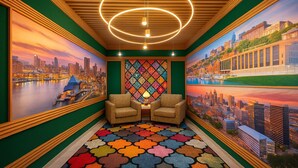 A room with two armchairs, a colorful carpet, and cityscape murals on the walls.
