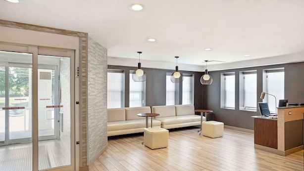 A modern reception area with a sofa, ottoman, and desk, large windows, and a patterned wall. - Best Western Plus Fairfield Hotel (Fairfield)
