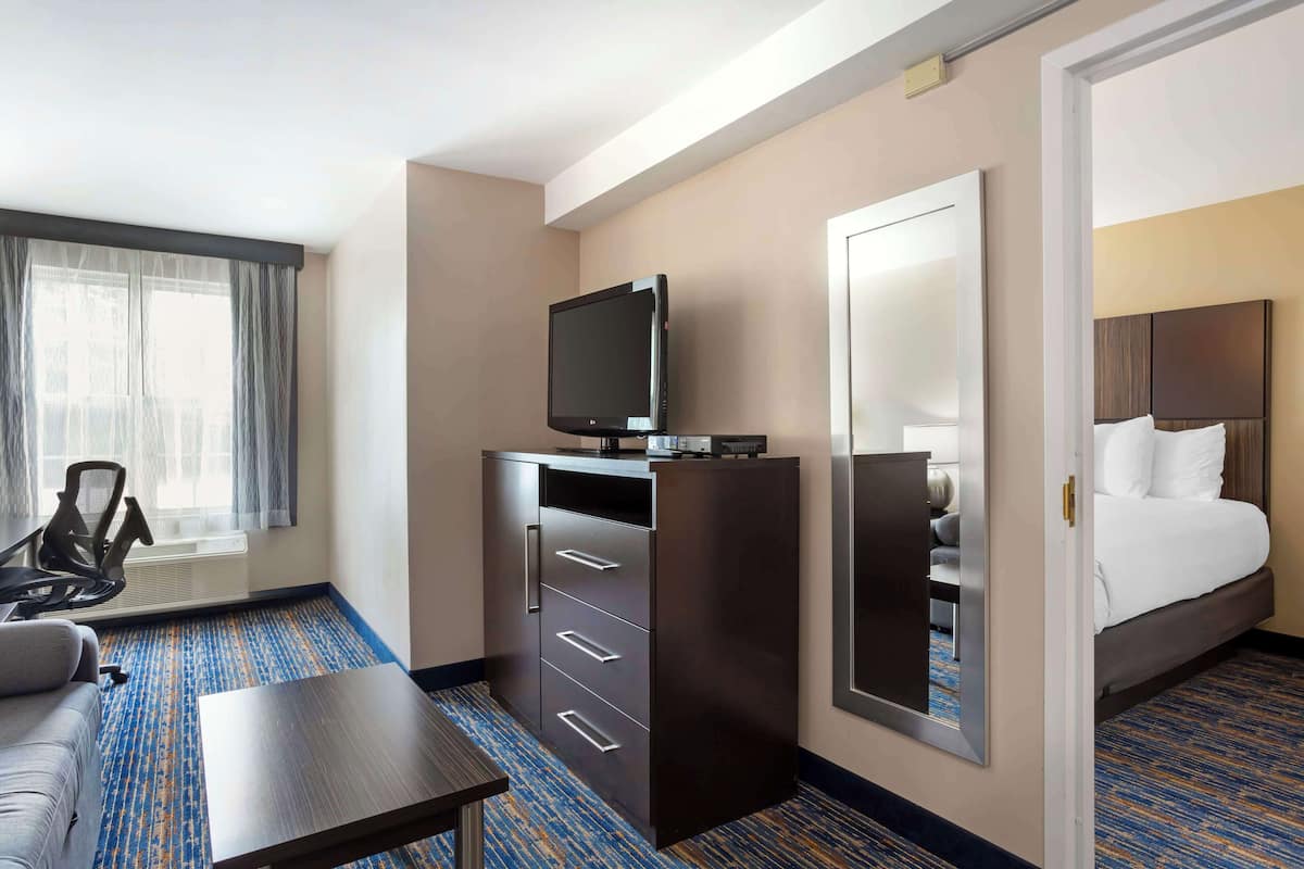 A hotel room with a bed, a TV on a cabinet, a desk, and a chair.