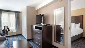 Una habitación de hotel con una cama, un televisor en un mueble, un escritorio y una silla.