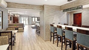 A modern dining area with a long table and chairs, a sofa, and a chandelier. - Best Western Plus Fairfield Hotel (Fairfield)