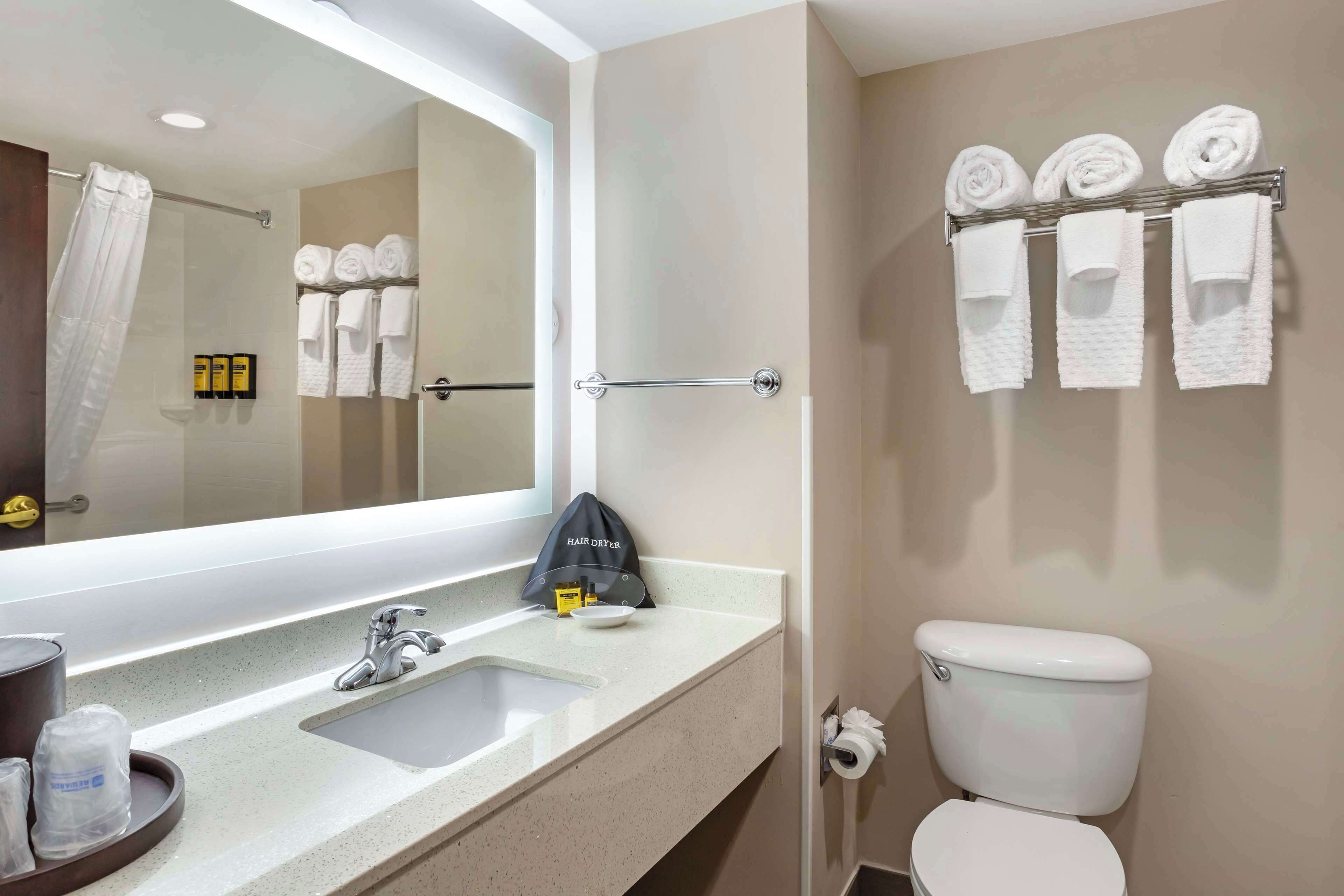 A bathroom with a sink, mirror, towel rack, and toilet.