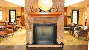 A lobby with a stone fireplace, wooden chairs, and a carpeted floor. - Staybridge Suites Houston Willowbrook by IHG (Houston)