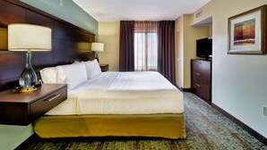 A hotel room with a large bed, two bedside tables with lamps, a dresser, a television, and a framed picture on the wall. - Staybridge Suites Houston Willowbrook by IHG (Houston)