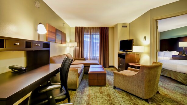 A hotel room with a bed, a desk, a chair, a TV, and a window with curtains. - Staybridge Suites Houston Willowbrook by IHG (Houston)