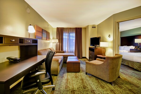 A hotel room with a bed, a desk, a chair, a TV, and a window with curtains. - Staybridge Suites Houston Willowbrook by IHG (Houston)