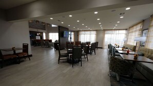 Un amplio vestíbulo de hotel con varias zonas de estar, una recepción y una pantalla de televisión.