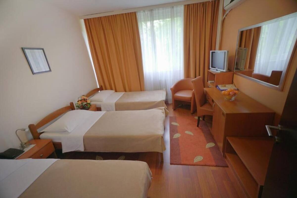 A hotel room with two beds, a desk, a chair, a television, and a mirror.