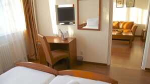 Una habitación de hotel con cama, escritorio, silla, televisor y sofá.