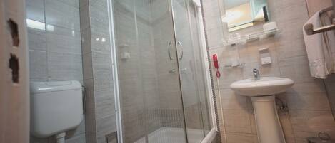 A modern bathroom with a glass-enclosed shower, a white toilet, and a pedestal sink.