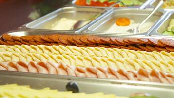 En buffet med et udvalg af madvarer, herunder kød, oste og frugt.
