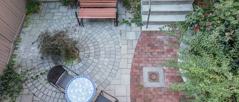 Un patio con una mesa circular, dos sillas, un banco y un sendero de ladrillos.