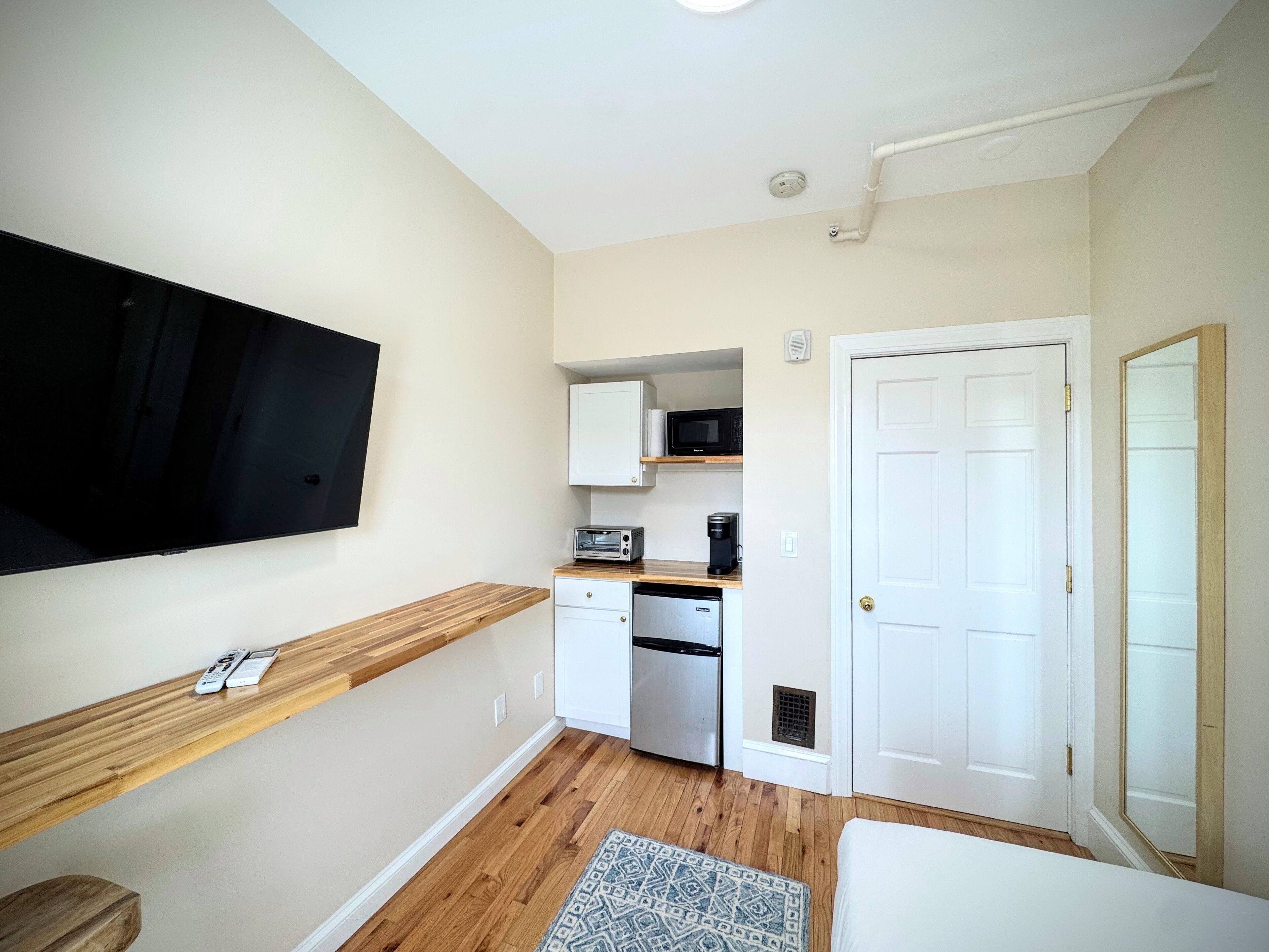A compact kitchen with a microwave, toaster, and coffee maker on a wooden countertop.