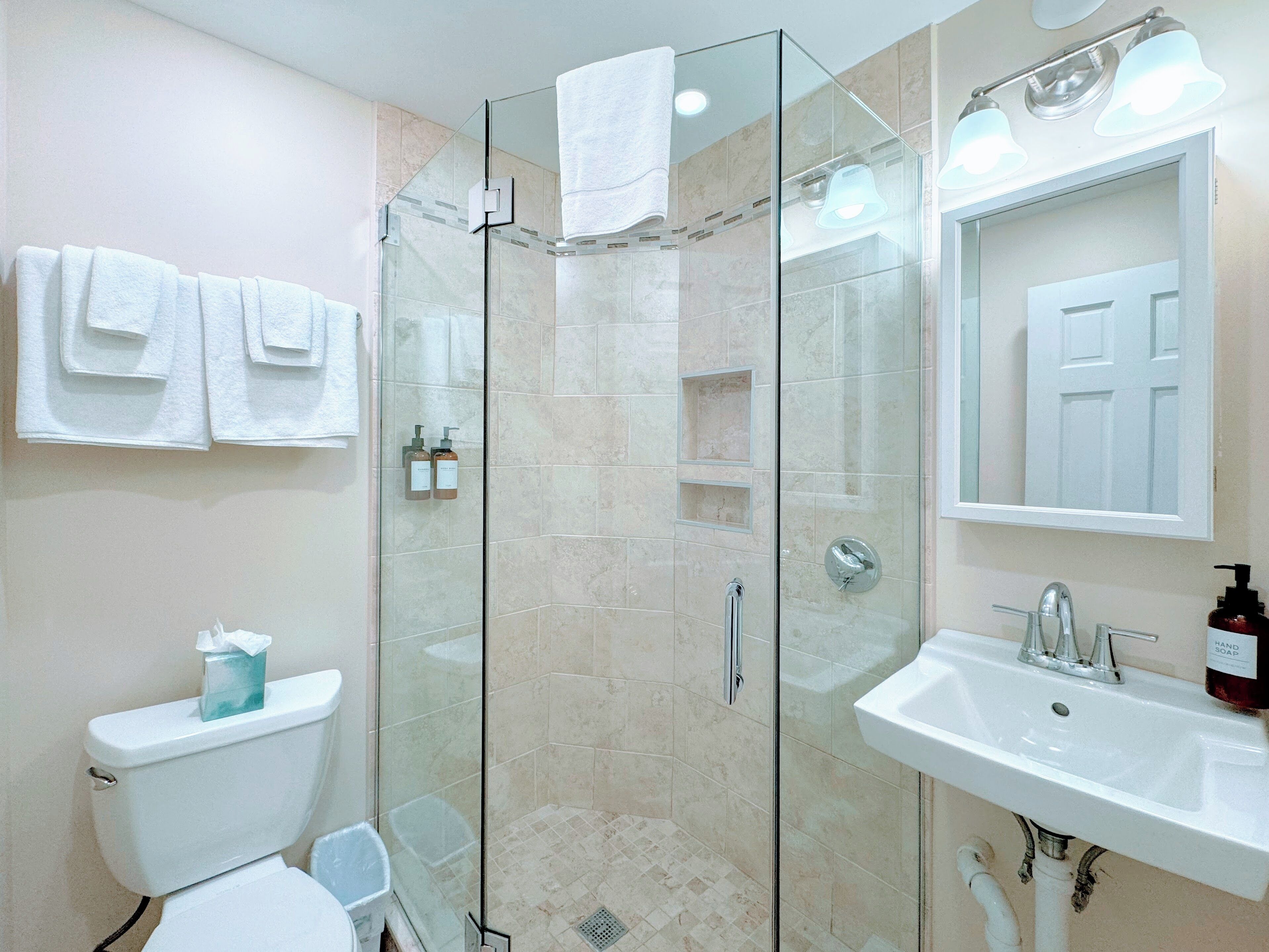 Une salle de bain moderne avec une douche à parois de verre, un lavabo blanc et des toilettes.