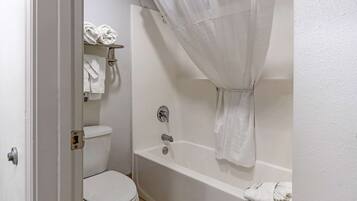 A bathroom with a white toilet, a bathtub with a shower curtain, and a towel rack with towels.