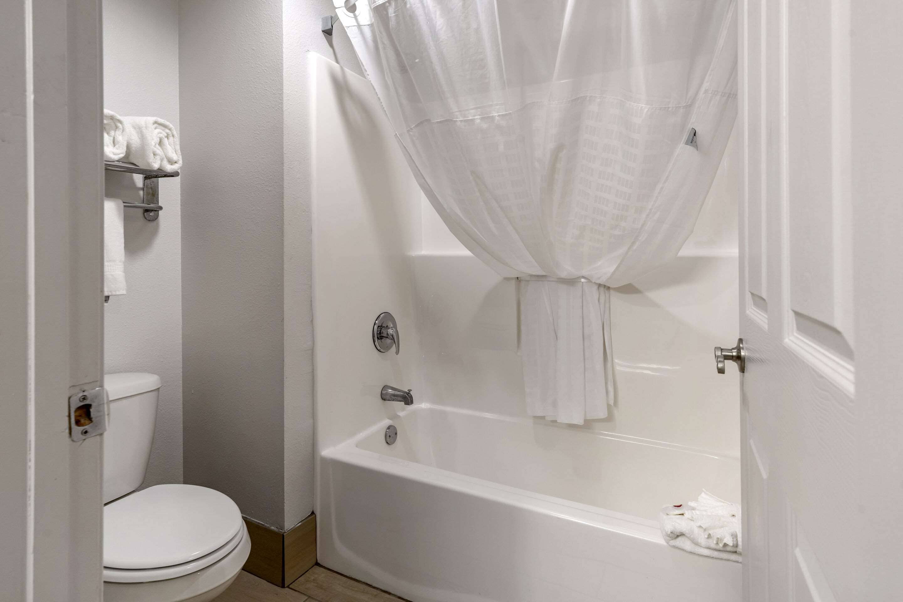 A bathroom with a white bathtub, a toilet, and a shower curtain.