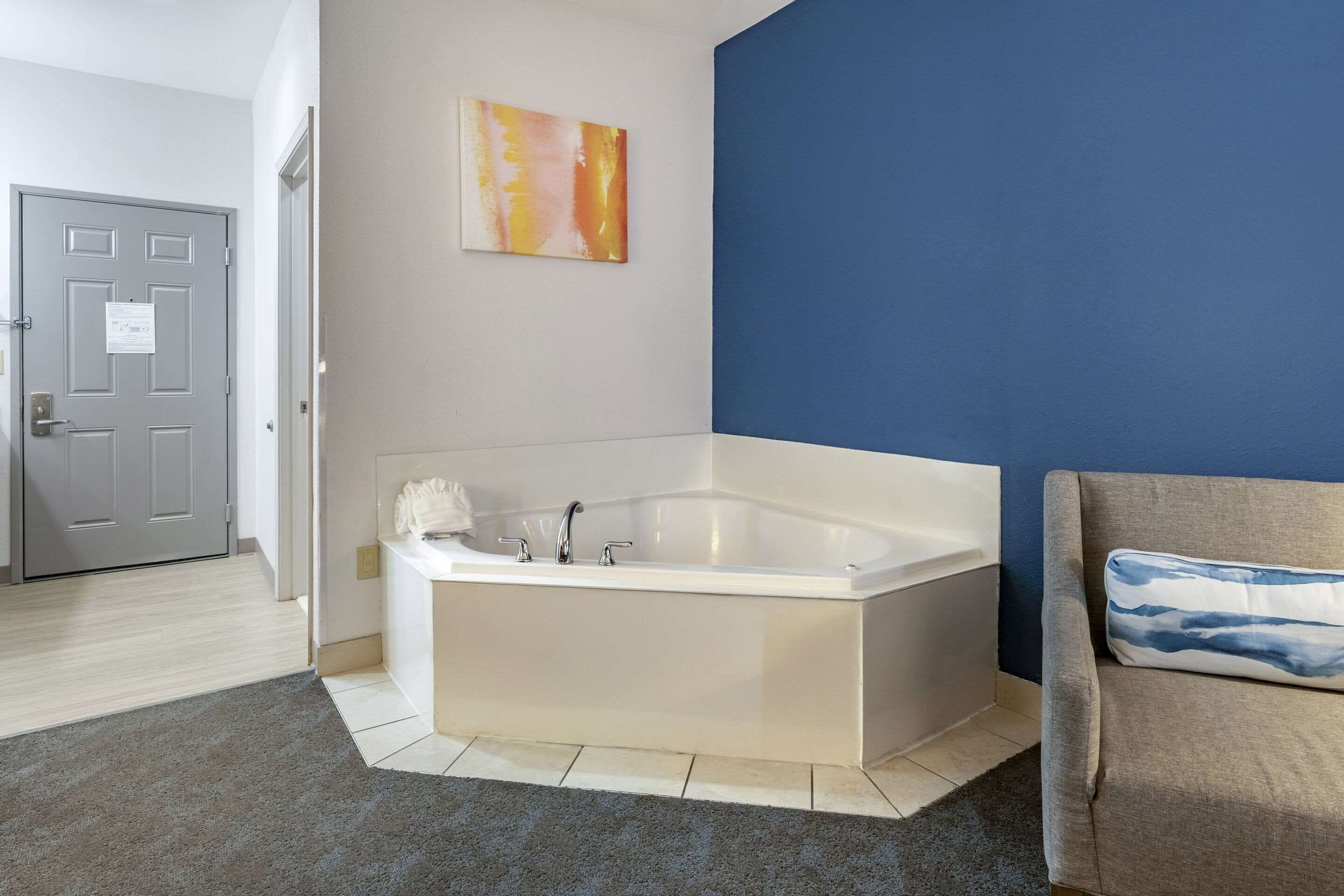 Ein modernes Badezimmer mit einer freistehenden Badewanne, einer grauen Tür und einer blauen Akzentwand.