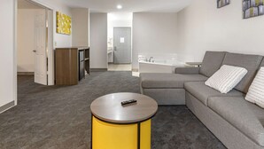 A modern living room with a grey sofa, a yellow side table, and a remote control on the table. - Comfort Inn & Suites Shelbyville (Shelbyville)