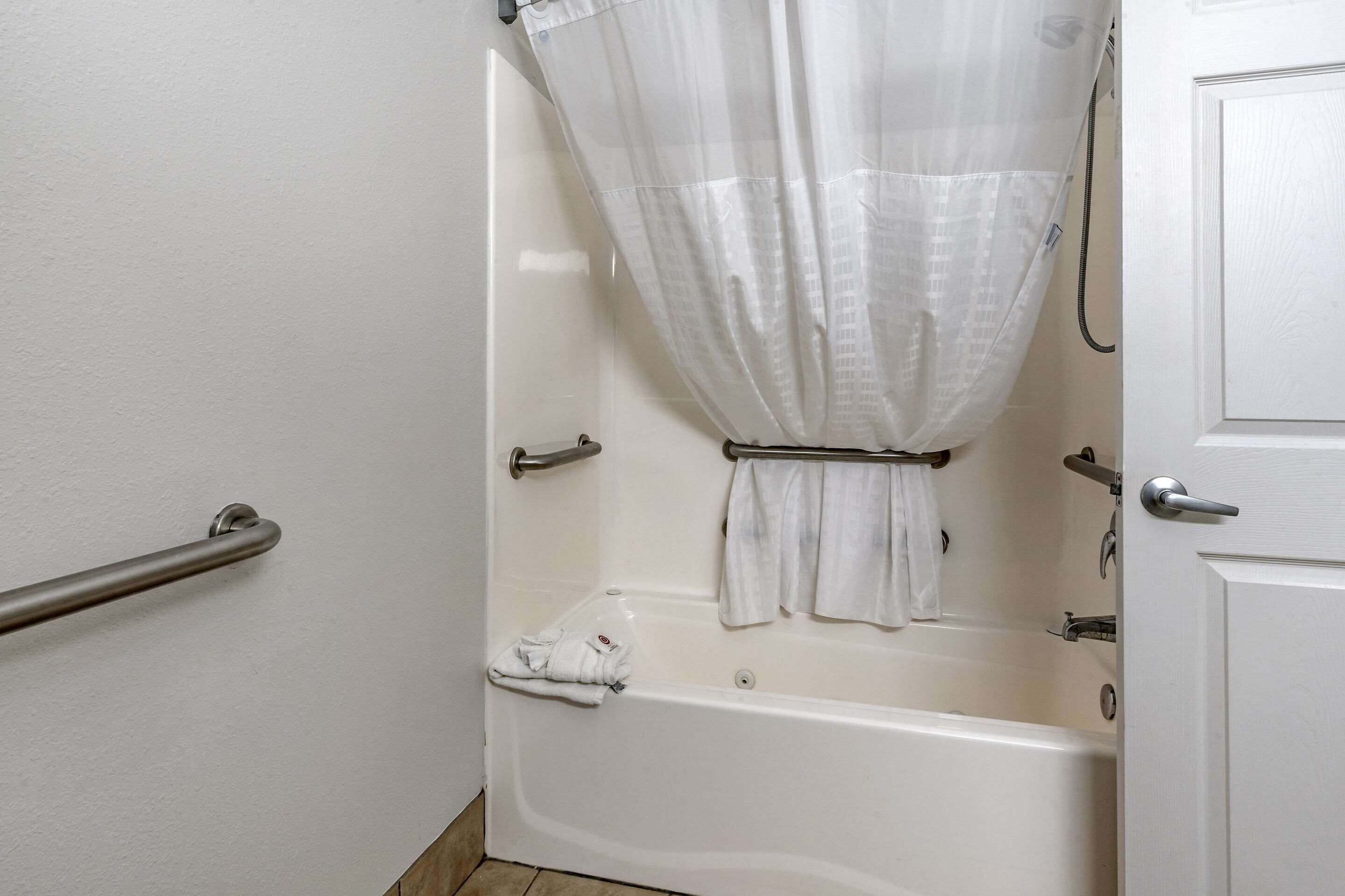 A bathroom with a bathtub, a shower curtain, and a towel rack.