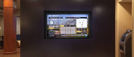 A digital display in a lobby with a GoBoard interface, including a weather forecast, news, and a map.