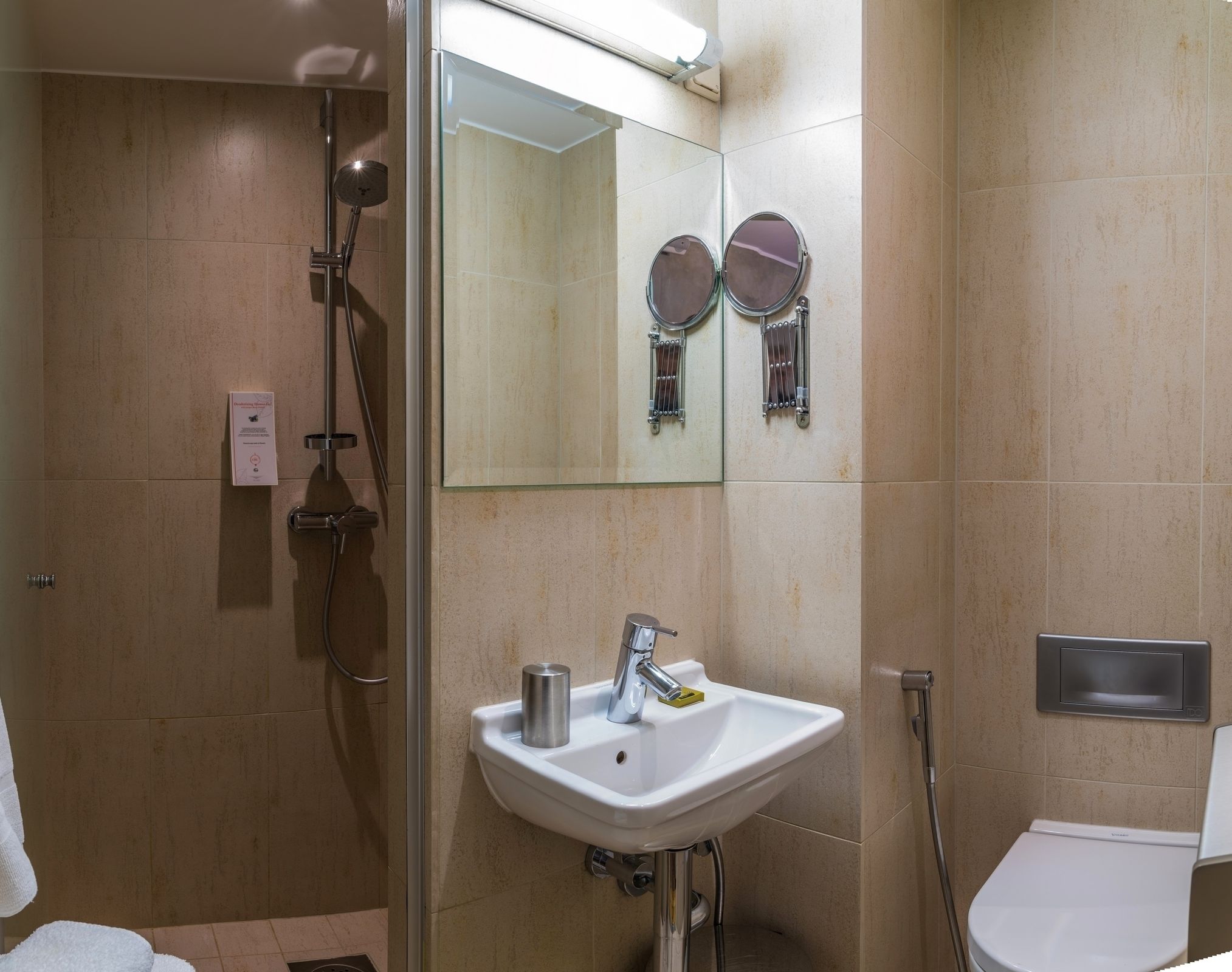 A modern bathroom with a glass-enclosed shower, a white sink with a mirror above it, and a toilet.