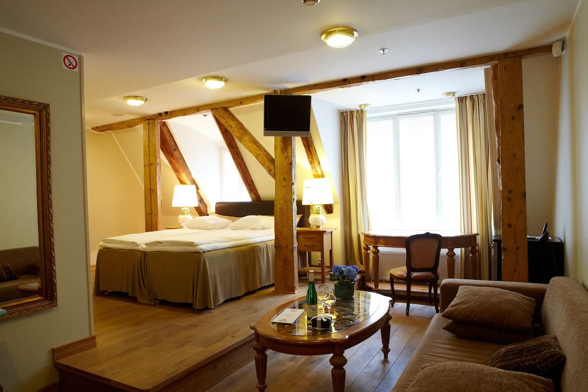 A hotel room with a bed, a TV, a desk, a chair, and a sofa.