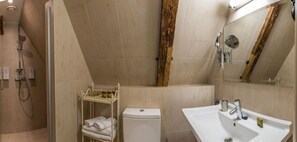 A bathroom with a shower, toilet, sink, and a wooden accent wall. - CRU Hotel (Tallinn)