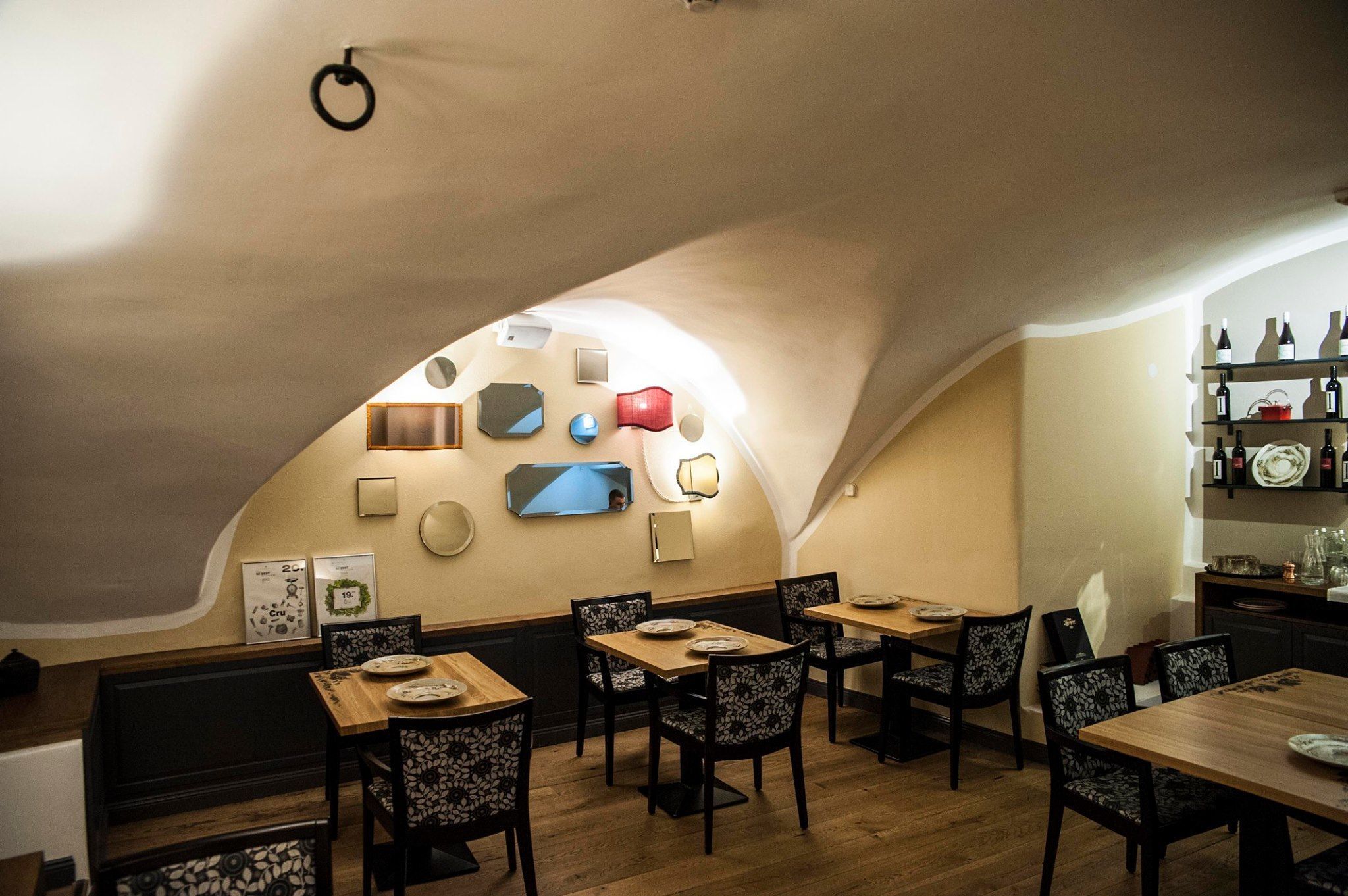 A restaurant with a curved ceiling, wooden tables and chairs, and wall-mounted decor.