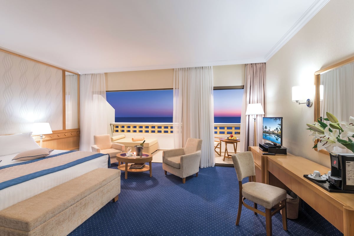 Une chambre d’hôtel comprenant un lit, un bureau, une chaise, une petite table et un téléviseur.