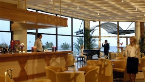En hotellobby med en bardisk, sittplatser och ett piano.