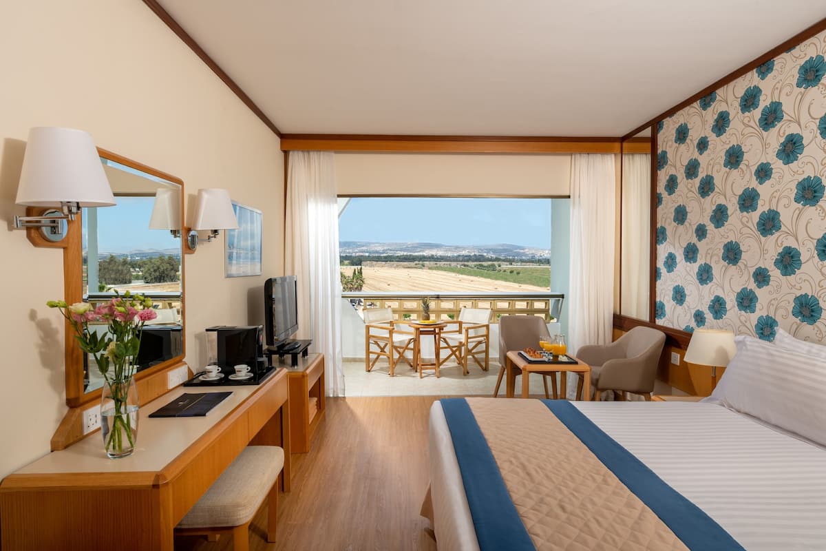 Une chambre d’hôtel avec un lit, un bureau, une chaise et un balcon offrant une vue.