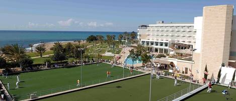 A sports field with a view of the ocean and a hotel in the background.