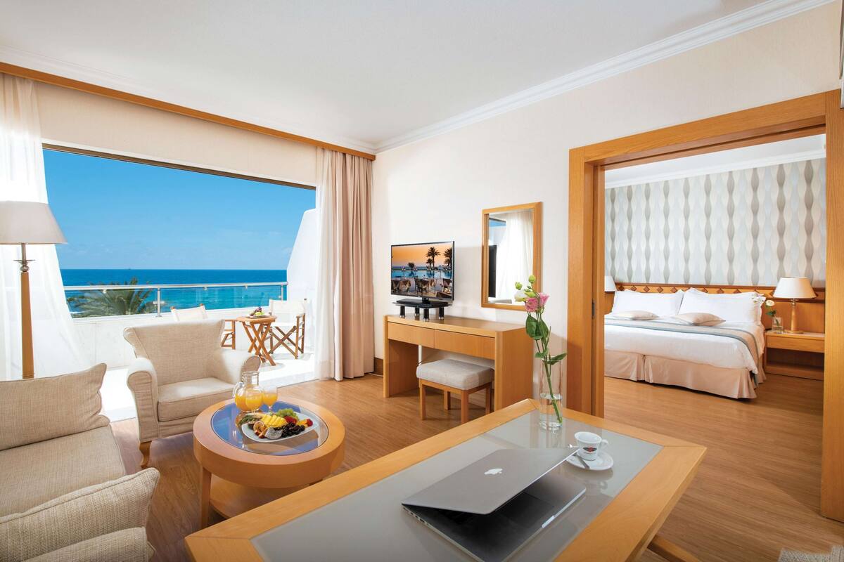 Ein Hotelzimmer mit großem Fenster, einem Schreibtisch, einem Bett und einer Sitzecke.
