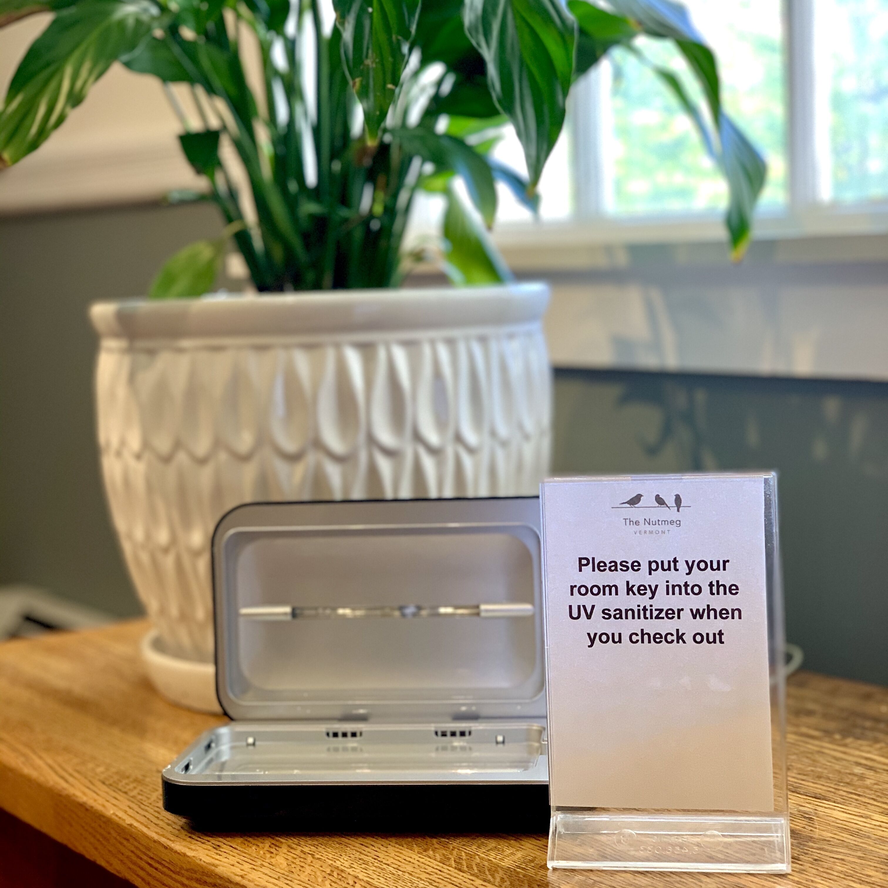 A room key holder with a sign instructing to put the room key into the UV sanitizer upon check-out.