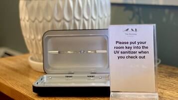 A room key holder with a sign instructing to put the room key into the UV sanitizer upon check-out.