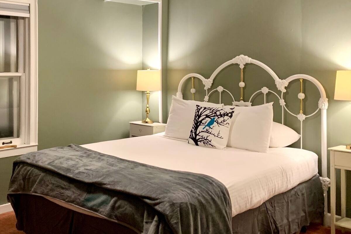 A bedroom with a bed, nightstands, a lamp, and a ceiling fan.