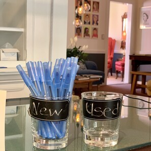 Two glass jars on a table, one labeled "New" with blue pens and the other labeled "Used" with clear liquid. - The Nutmeg (Wilmington)