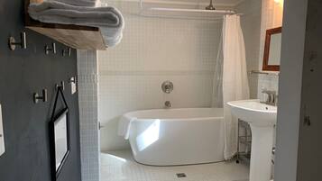 A modern bathroom with a bathtub, shower, and sink.