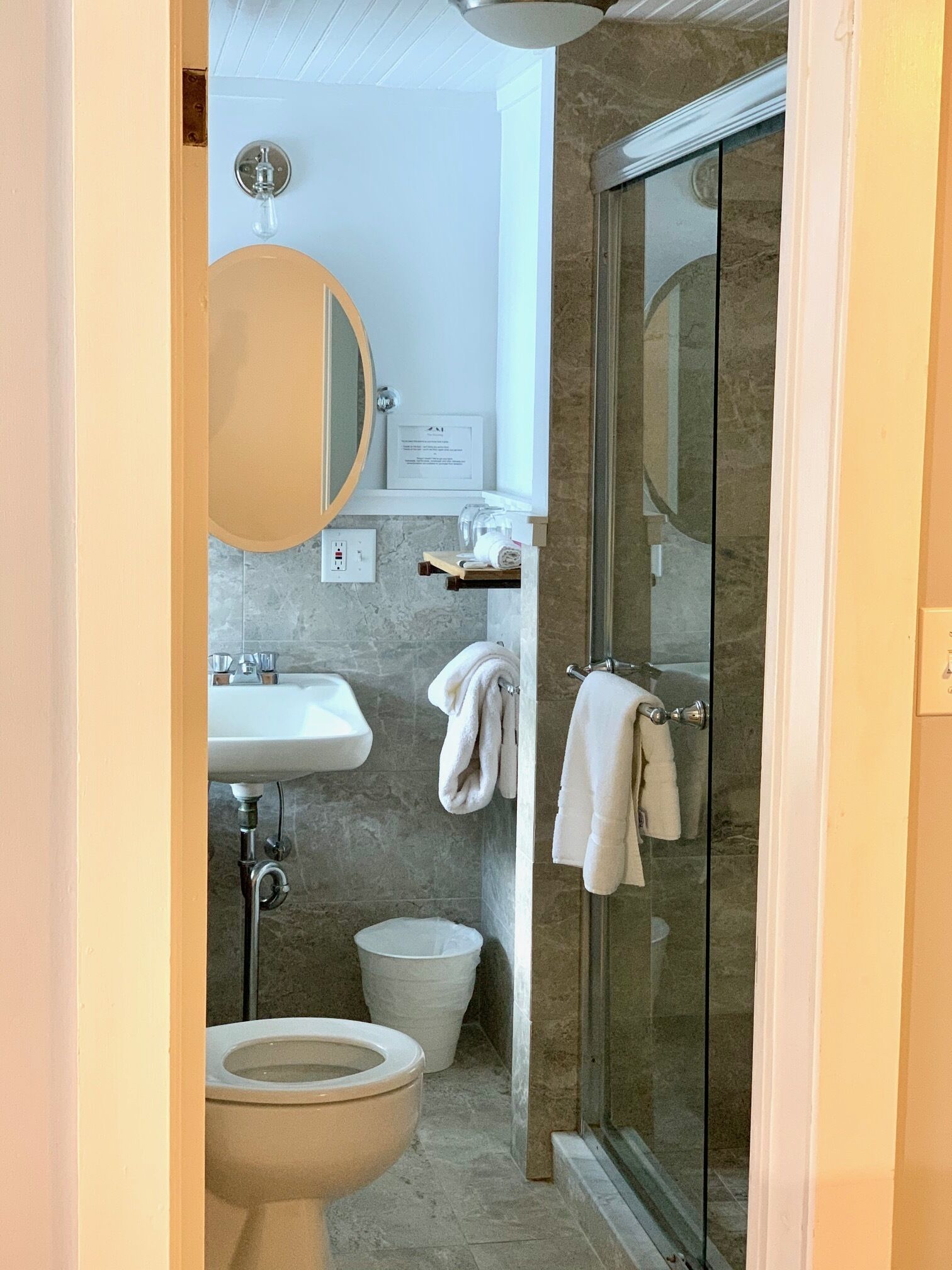 A bathroom with a toilet, sink, and glass shower enclosure.