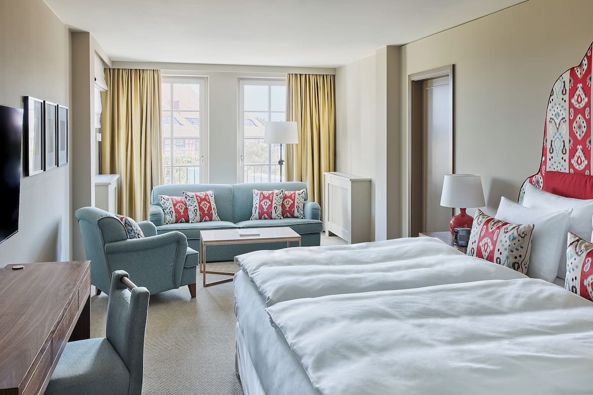 Ein Hotelzimmer mit einem großen Bett, einer Sitzecke, einem Schreibtisch und einem Fernseher.