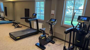 Une salle de sport équipée de tapis de course, de vélos elliptiques et d’un vélo d’appartement.