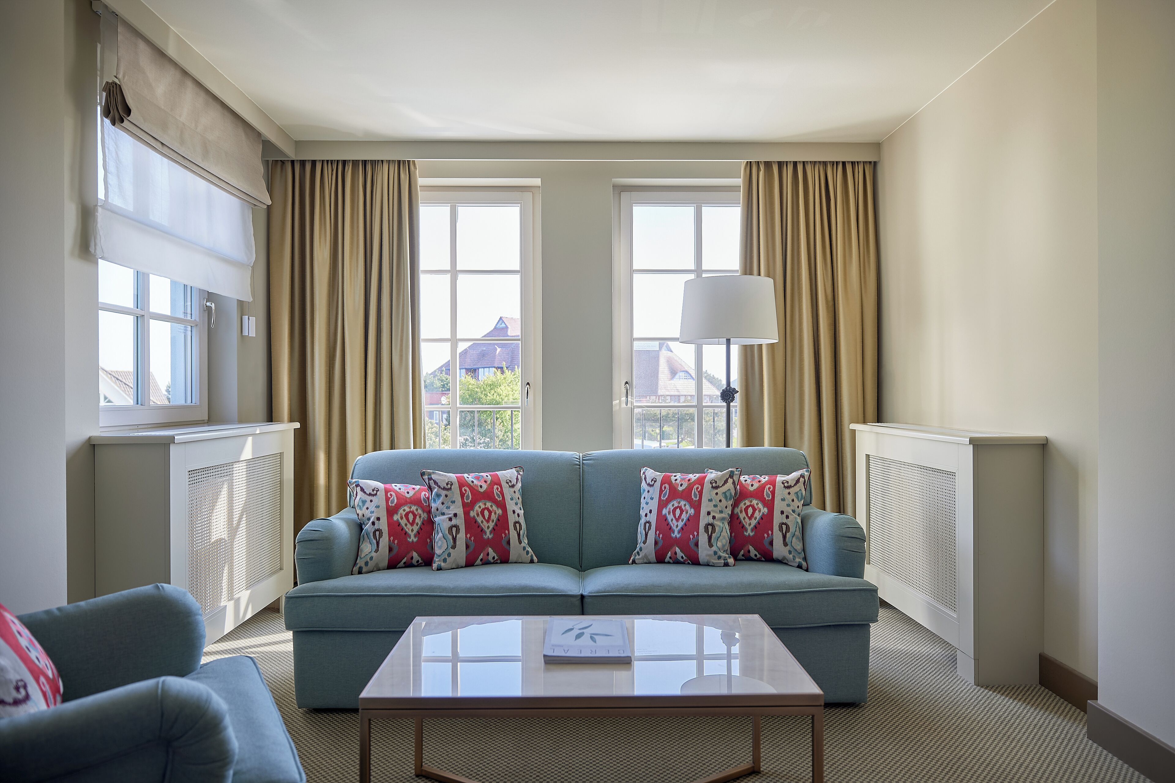 A modern living room with a light blue sofa, two patterned throw pillows, a white coffee table, and a floor lamp.
