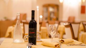 A dining table with a bottle of wine, a candle, and a glass.