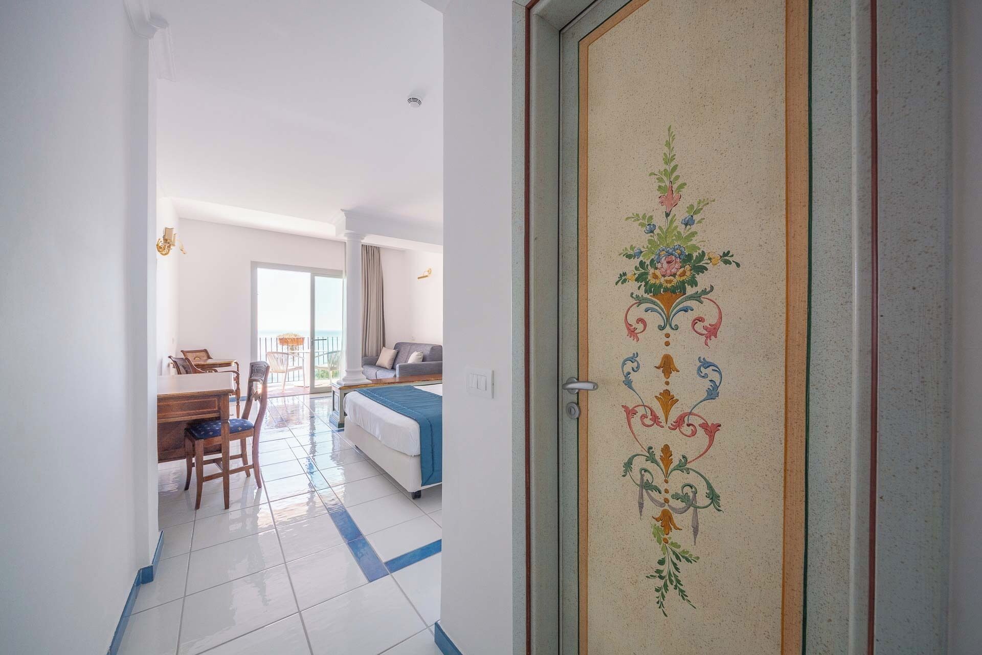 Habitación de hotel con cama, escritorio y silla. Tiene un balcón con vistas.