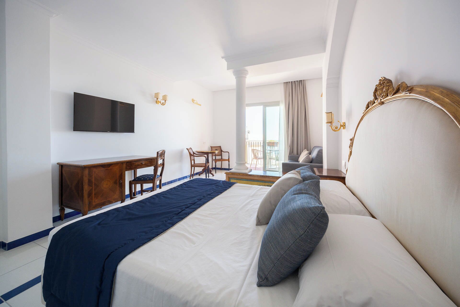 Une chambre d’hôtel équipée d’un lit, d’un bureau, d’une chaise, d’une télévision et d’un balcon avec vue.