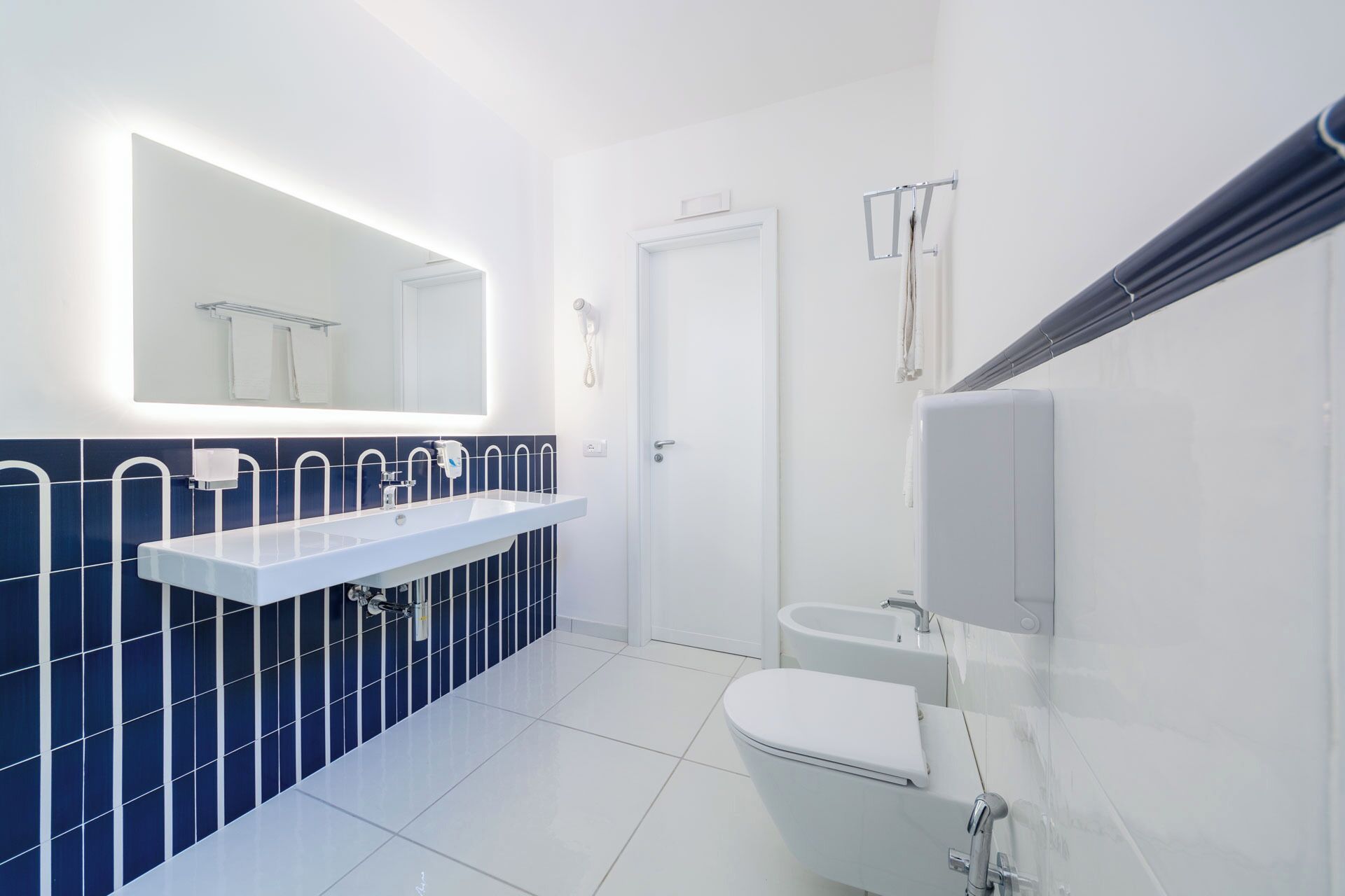 Ein modernes Badezimmer mit Waschbecken, separatem Waschtisch, Toilette und Duschbereich.