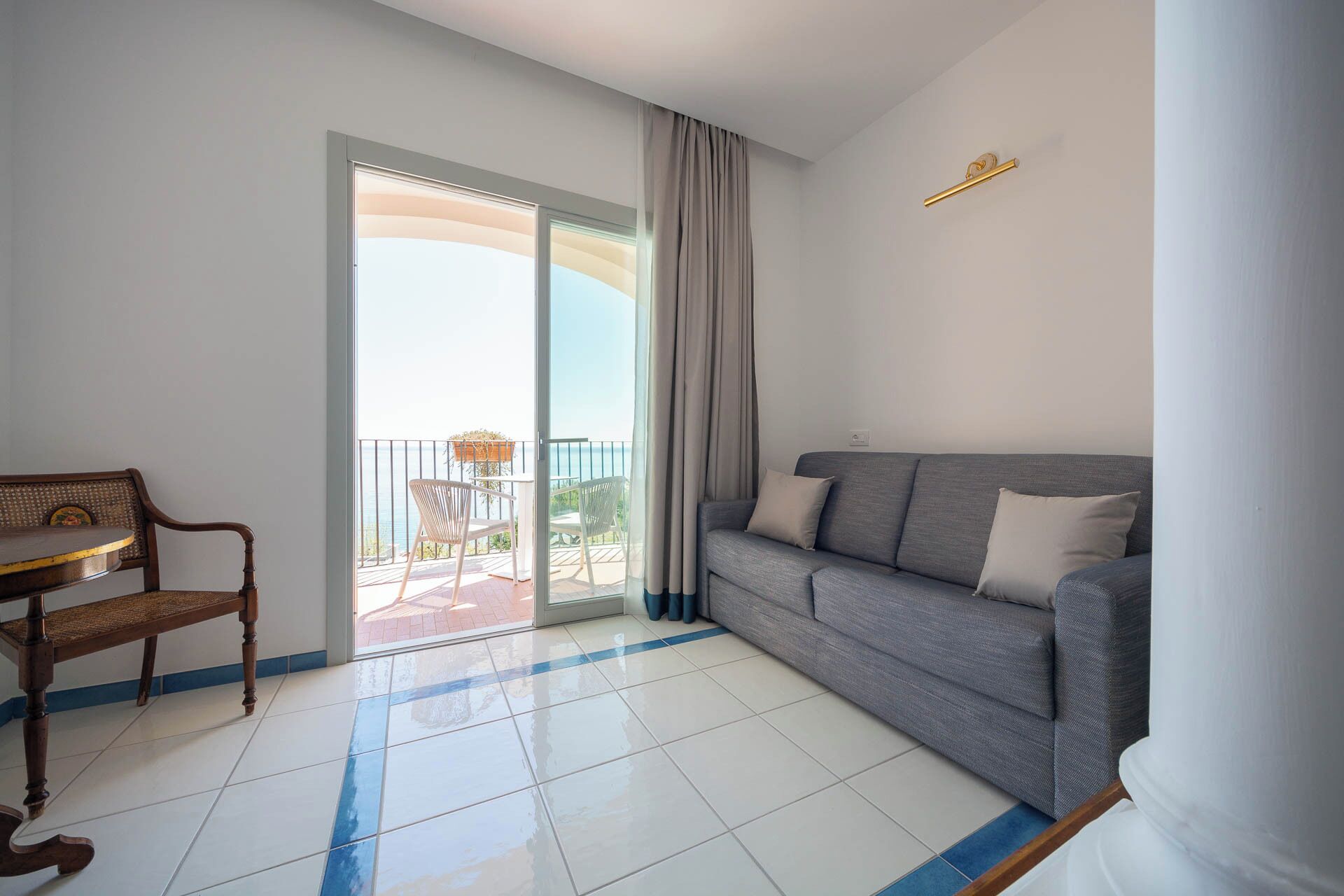 Una sala de estar moderna con un sofá gris, una silla de madera y un balcón con vistas.