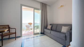 Una sala de estar moderna con un sofá gris, una silla de madera y un balcón con vistas.