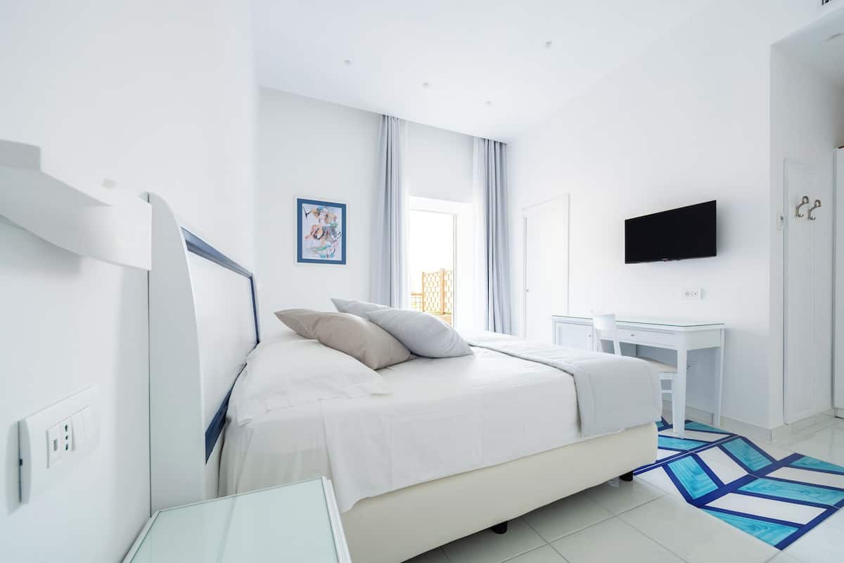 A modern bedroom with a bed, a desk, a TV, and a staircase.