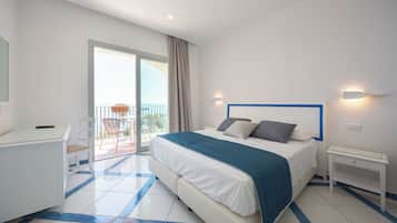 Una camera d'albergo con un letto, una scrivania e un balcone con vista.